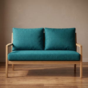 May include: A two-seater sofa featuring a light-toned wooden frame with straight armrests and legs. The sofa includes two large, plush back cushions and a single long seat cushion, all upholstered in a textured, deep teal fabric.
