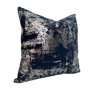 May include: A navy blue throw pillow with a silver metallic abstract design. The pillow is made of a soft, textured fabric.