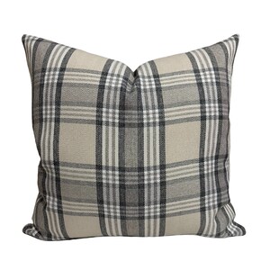 May include: A beige and black plaid throw pillow with a square shape.