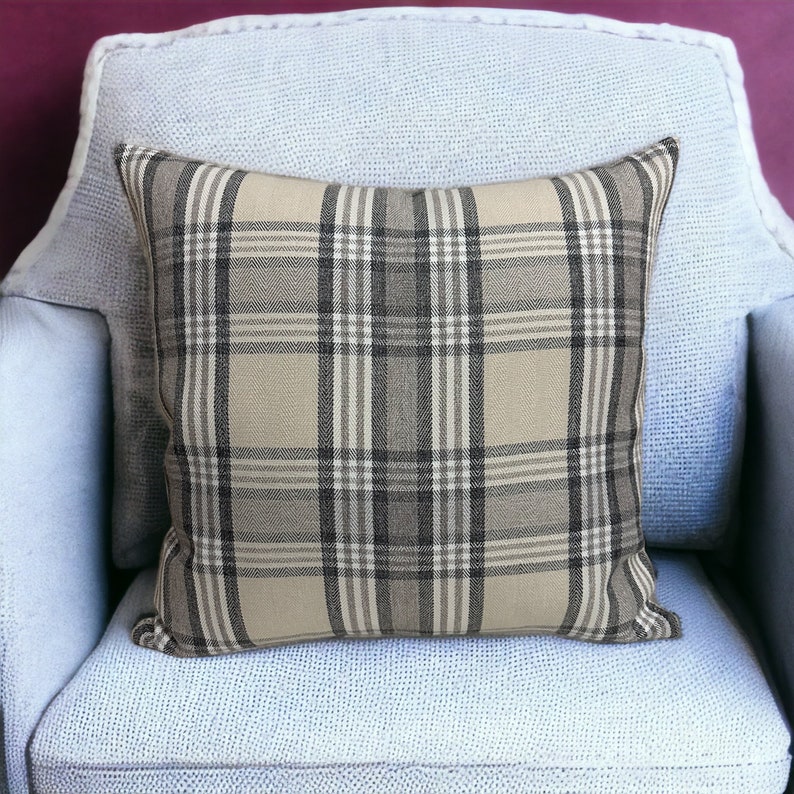 May include: A beige and black plaid throw pillow on a light blue armchair.