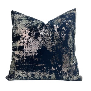 May include: A navy blue throw pillow with a silver metallic abstract pattern.