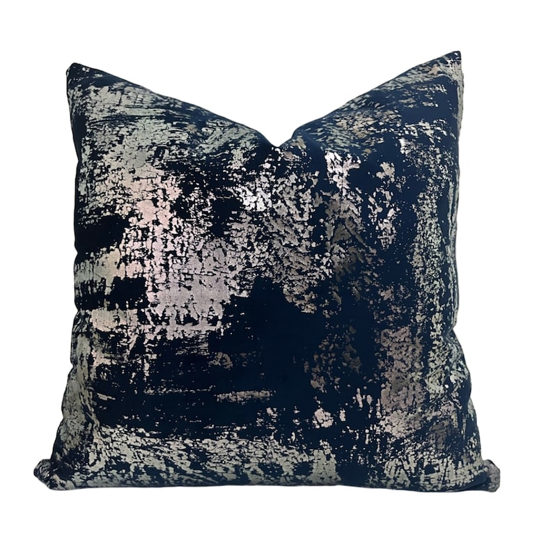 May include: A navy blue throw pillow with a silver metallic abstract pattern.