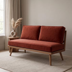 K&ouml;nnte beinhalten: Ein Zweisitzer-Sofa mit einem Holzrahmen, konisch zulaufenden Beinen und einem weichen, rostfarbenen Samtbezug. Das Design umfasst zwei rechteckige R&uuml;ckenkissen und ein langes Sitzkissen, die eine klare und strukturierte Form bilden.