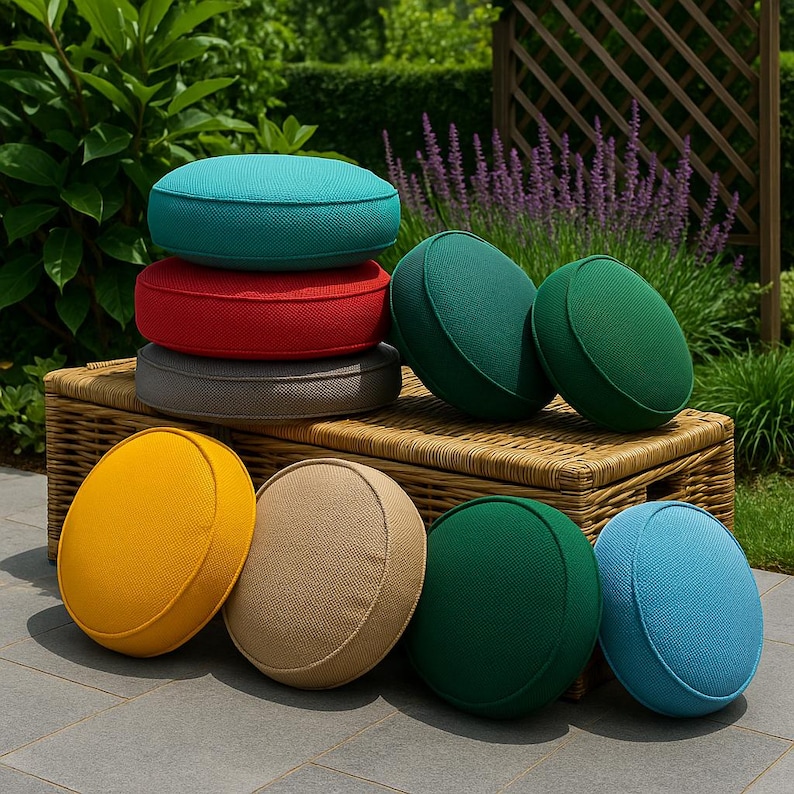 May include: A collection of round, textured cushions in various solid colors including turquoise, red, gray, yellow, beige, and shades of green. The cushions are arranged in a stack and placed upright on a woven wicker bench in an outdoor setting.