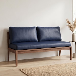 May include: A two-seater sofa featuring a dark navy blue leather upholstered seat and backrest cushions. The frame is constructed from natural brown wood with four straight legs, providing a sturdy base for the smooth, matte-finish cushions.