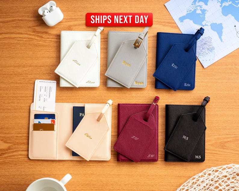 Puede incluir: Una colecci&oacute;n de accesorios de viaje personalizados, que incluyen fundas para pasaportes y etiquetas de equipaje, en varios colores como blanco, gris, azul marino, burdeos y negro. Cada art&iacute;culo est&aacute; grabado con un nombre o iniciales en letras doradas.