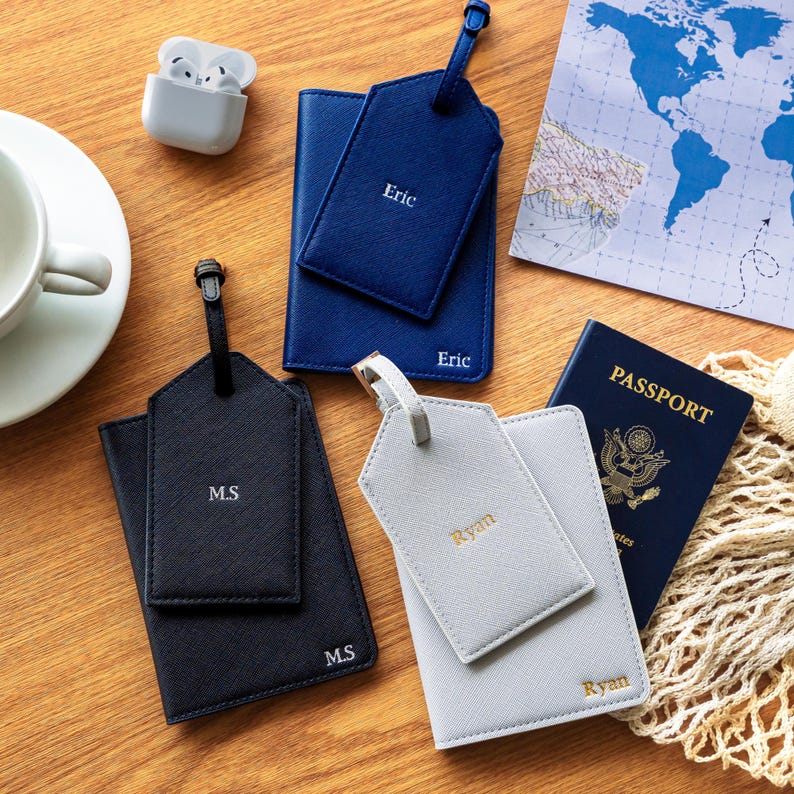 Puede incluir: Una colecci&oacute;n de accesorios de viaje, que incluye un tarjetero y etiqueta de equipaje azul marino con "Eric" impreso, un tarjetero y etiqueta de equipaje negro con "M.S" impreso y un tarjetero y etiqueta de equipaje gris con "Ryan" impreso.