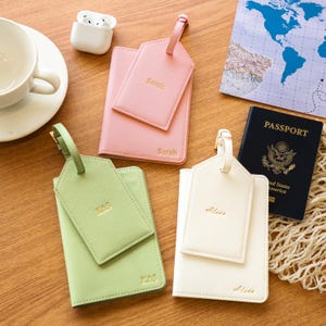 Puede incluir: Un conjunto de accesorios de viaje, que incluyen fundas para pasaporte y etiquetas para equipaje en rosa pastel, verde claro y crema. Tambi&eacute;n hay un pasaporte negro. Las etiquetas de equipaje y los portapasaportes est&aacute;n personalizados con nombres.