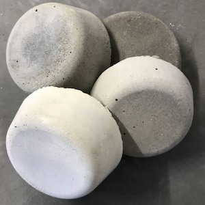 May include: Four round concrete planters in various shades of gray. The planters are smooth and have a slightly textured surface.