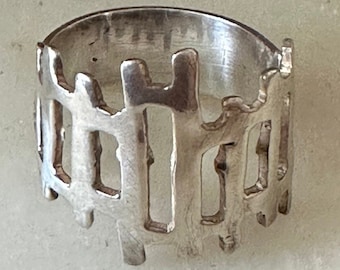 May include: A silver ring with a unique design that resembles a fence. The ring is made of metal and has a textured surface.