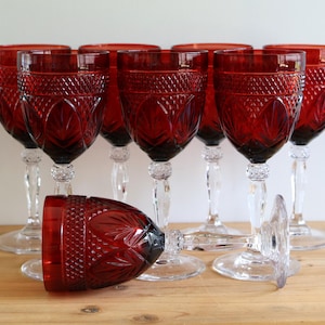Può includere: Set di otto bicchieri da vino rosso con un motivo a diamante. I bicchieri hanno steli e basi trasparenti.