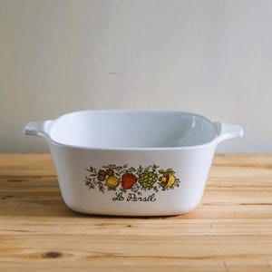 May include: White ceramic baking dish with a floral design featuring vegetables and the text "Le Persil".