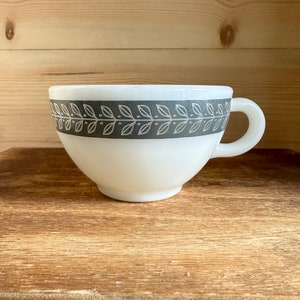 May include: White ceramic mug with a grey and white leaf pattern around the rim.