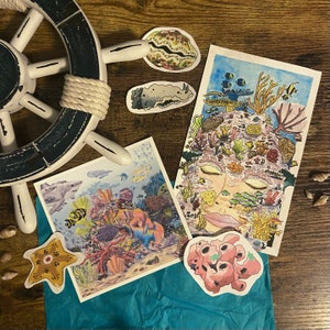 May include: A set of colorful stickers featuring underwater scenes. The stickers include a mermaid face, a coral reef with fish, a starfish, and a seahorse. The stickers are perfect for adding a touch of whimsy to your journals, laptops, or water bottles.