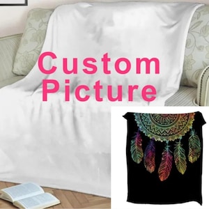 May include: A white fleece blanket with the text "Custom Picture" printed in pink. A second image shows a black fleece blanket with a colorful dreamcatcher design.