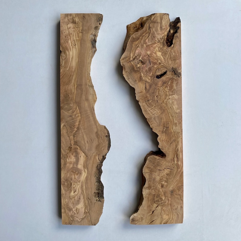 May include: Two irregularly shaped, light brown wooden planks with natural edges. The wood grain is visible, with variations in colour and texture. The planks are displayed against a white background, showcasing their organic form and unique character.