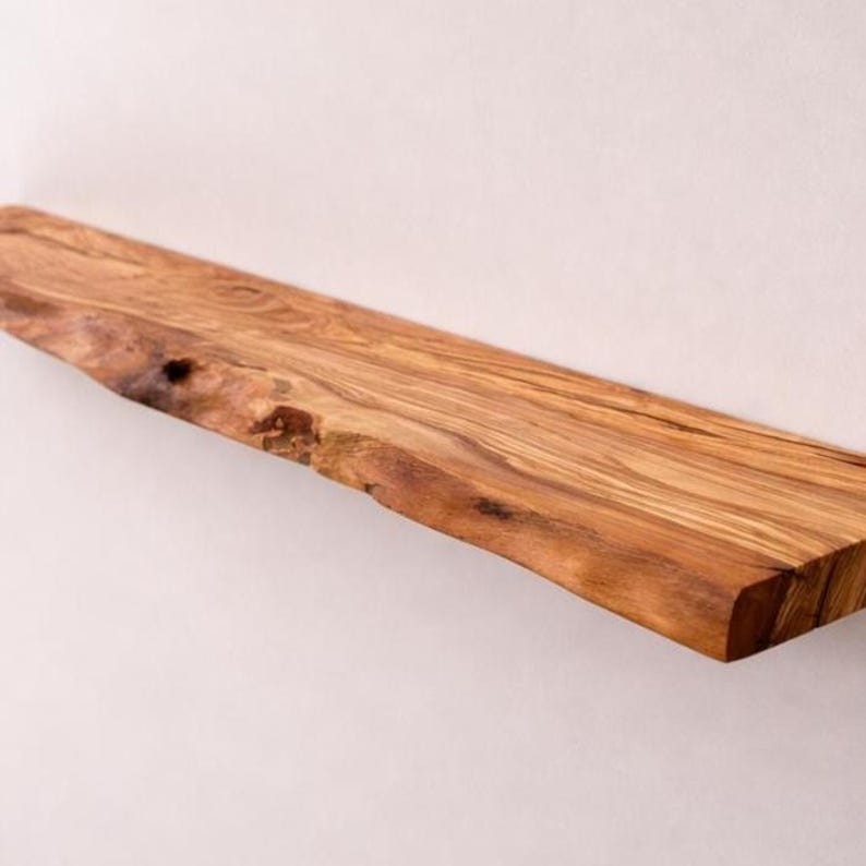 May include: A rectangular wooden shelf featuring a natural live edge along the front side. The wood displays a prominent grain pattern with warm brown and golden tones, showcasing the organic texture and knots inherent to the timber material.