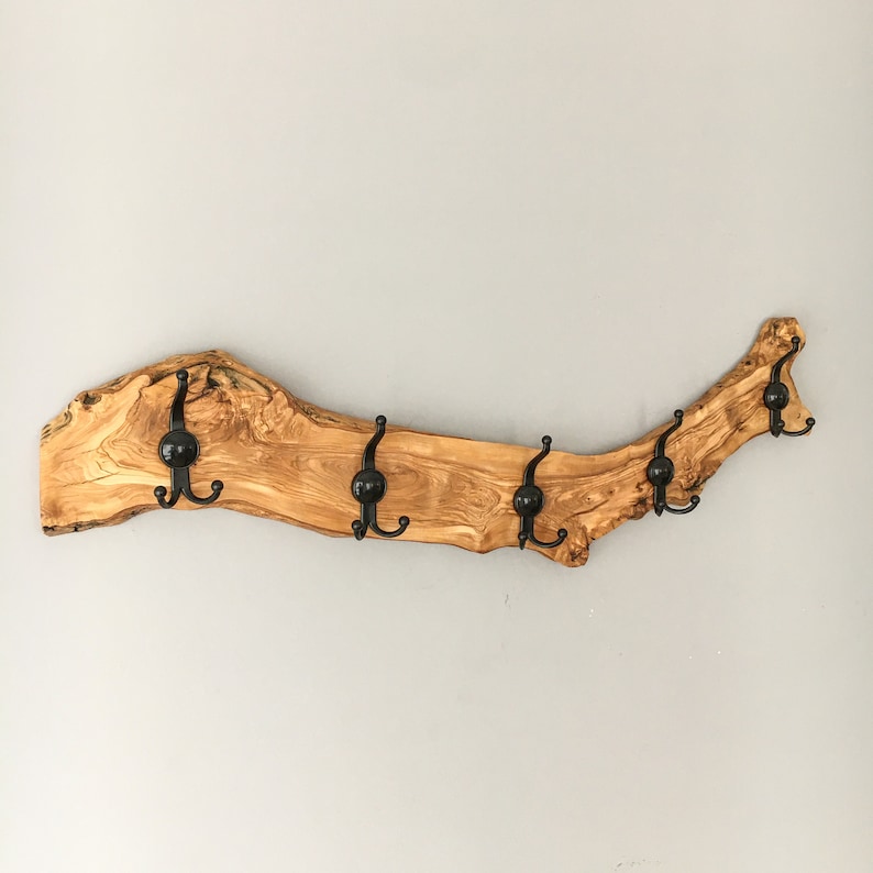 May include: A rustic wooden coat rack with six black metal hooks. The rack is made from a single piece of light brown wood with a natural, irregular shape. The hooks are evenly spaced along the length of the wood.