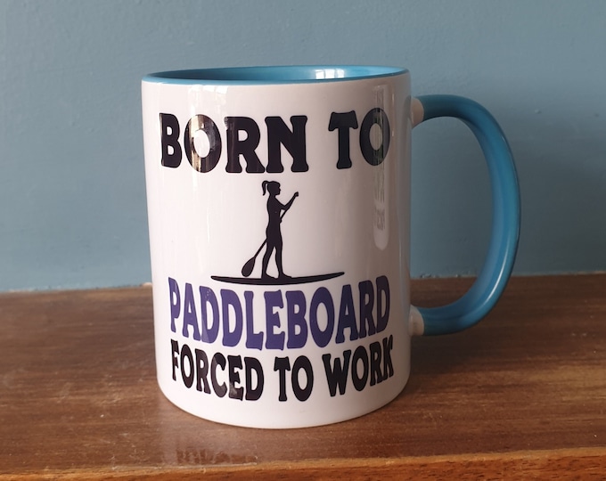 Paddleboarder mug with humourous theme and the wording 'Born to Paddleboard, Forced to work'