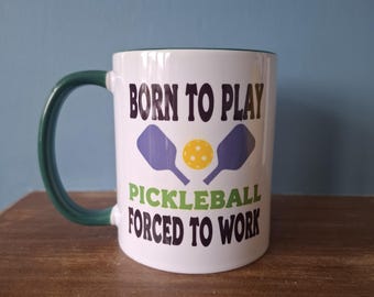 Pickleball mug with humourous theme and the wording 'Born to Play Pickleball, Forced to work'