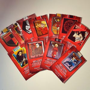 May include: A collection of red Hellsing Collection magnetic bookmarks. Each bookmark features a different anime character illustration. Text on the bookmarks includes "HELLSING COLLECTION", "Embrace the darkness within", and "Magnetic Bookmark".