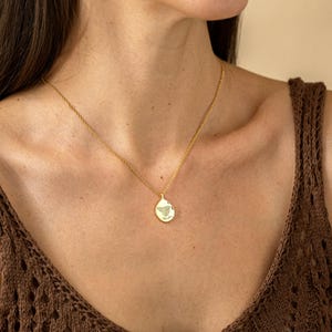 K&ouml;nnte beinhalten: Eine goldfarbene Halskette mit einem Anh&auml;nger mit einem Schmetterlingsdesign. Der tropfenf&ouml;rmige Anh&auml;nger h&auml;ngt an einer feinen Kette. Die Halskette wird um den Hals getragen.