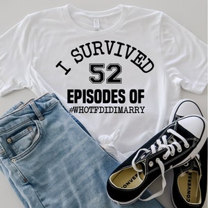 May include: White t-shirt with black text that reads "I survived 52 episodes of #WHOTFDIDIMARRY". The shirt is paired with blue jeans and black sneakers.
