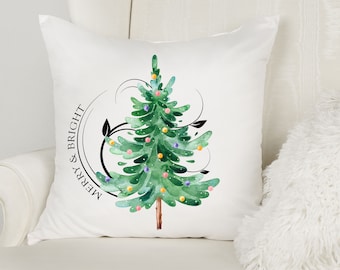 May include: White cushion featuring a green watercolour Christmas tree adorned with colourful baubles and the text "Merry & Bright" in a black circle.