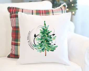 May include: White throw pillow featuring a green watercolour Christmas tree with colourful baubles and the text "Merry & Bright" in a circle around the tree.