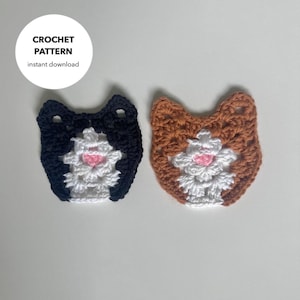 May include: Two crocheted cat faces, one black and white and one brown and white.
