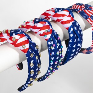 May include: Three headbands with a red, white, and blue American flag pattern. One headband has iridescent beads, one has rhinestones, and one has a simple flag pattern.