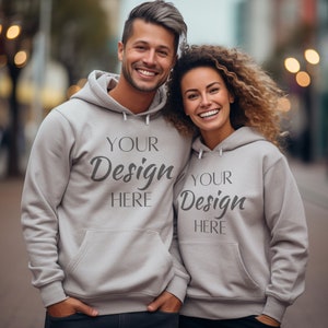 May include: Two people wearing gray hooded sweatshirts with the text "Your Design Here" on them. They are standing in an urban setting.
