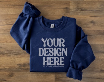 May include: A navy blue sweatshirt with the text "YOUR DESIGN HERE" in a light gray, retro font. The phrase "No AI Tricks, Just Real Picks" is below the main text. The sweatshirt is folded on a wooden surface.