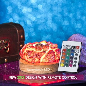 May include: A lava lamp shaped like a flower with a wooden base and a remote control. The lamp has a red and orange glow and is lit up. The remote control has buttons for different colors, light modes, and brightness.