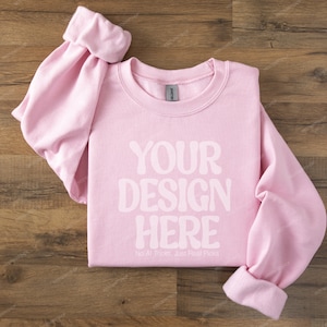 May include: A pink sweatshirt with the text "YOUR DESIGN HERE" and the words "No AI Tricks, Just Real Pics" printed on the front.