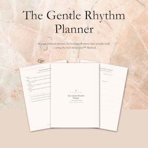 May include: A cream-colored planner titled "The Gentle Rhythm Planner" with the text "44-page undated planner for building rhythms that actually hold." The planner is open, revealing interior pages. The background is a marble-like texture.