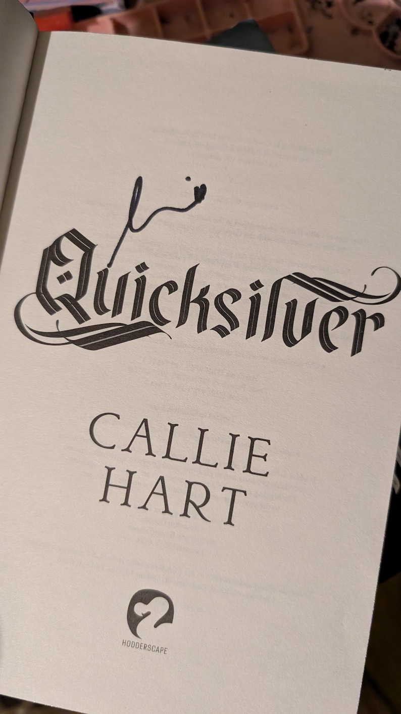 Puede incluir: P&aacute;gina de libro abierta con el t&iacute;tulo "Quicksilver" en una fuente ornamentada. El nombre del autor, Callie Hart, est&aacute; debajo. Un logotipo de "HODDERSCAPE" se encuentra en la parte inferior de la p&aacute;gina.