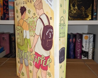 Könnte beinhalten: Band 3 des Graphic Novels Heartstopper von Alice Oseman. Das Cover zeigt zwei Figuren, eine mit blonden Haaren und die andere mit braunen Haaren, die zusammen gehen. Das Cover ist gelb mit grünen Blumen und der Titel ist in großen schwarzen Buchstaben.