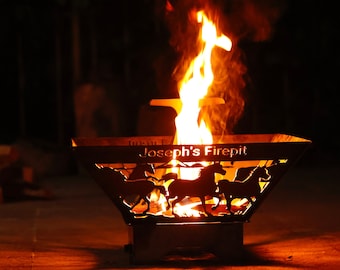 May include: A black metal fire pit with a cutout design of horses and the text "Joseph's Firepit". The fire pit is lit with flames and smoke rising from the center.