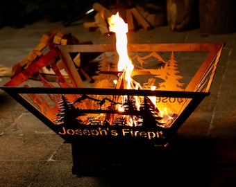 May include: A metal fire pit with a mountain scene design and the text "Joseph's Firepit". The fire pit is lit with flames rising from the center.