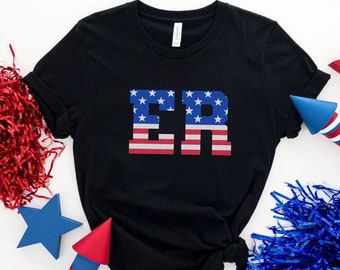 May include: A black t-shirt with the letters "ER" printed in red, white, and blue, resembling the American flag. The shirt is surrounded by red and blue confetti and a red star.
