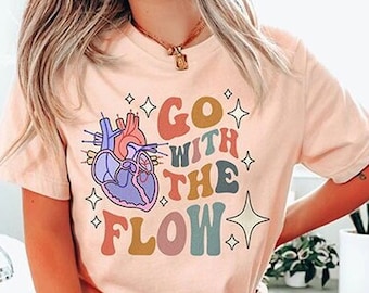 May include: A pink t-shirt with a graphic of a heart and the text "Go with the flow" in rainbow colors.