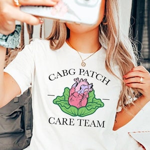 May include: White t-shirt with a graphic of a heart in a cabbage and the text "CABG PATCH CARE TEAM".