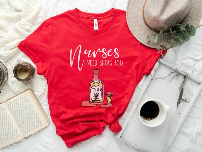 May include: Red t-shirt with the text "Nurses need shots too" and a cartoon illustration of a bottle of tequila and a shot glass.