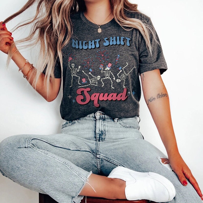 May include: A gray t-shirt with a graphic of skeletons wearing party hats and holding sparklers. The text "Night Shift Squad" is printed on the shirt in a retro font.