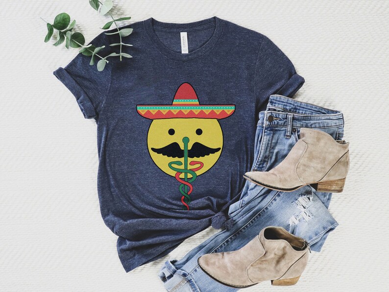 K&ouml;nnte beinhalten: Ein marineblaues T-Shirt mit einem gelben Smiley, der einen roten, gelben und gr&uuml;nen Sombrero tr&auml;gt. Der Smiley hat einen schwarzen Schnurrbart und eine gr&uuml;ne Schlange kommt aus seiner Nase.