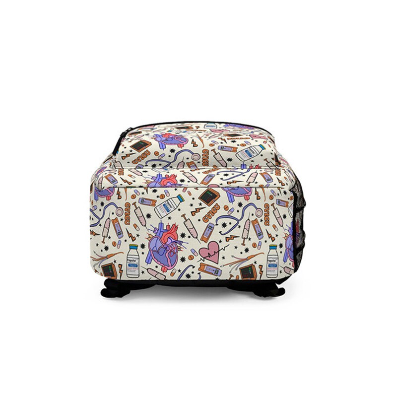 K&ouml;nnte beinhalten: Ein wei&szlig;er Canvas-Rucksack mit einem bunten Muster aus medizinischen Symbolen, darunter ein Herz, Pillen, Spritzen und ein Stethoskop. Das Muster wiederholt sich &uuml;ber den gesamten Rucksack.