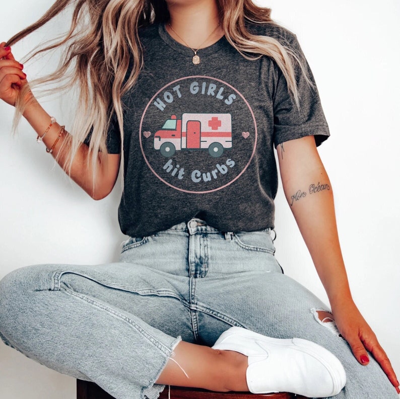 May include: A grey t-shirt with a pink and blue graphic of an ambulance with the text "Hot Girls Hit Curbs".