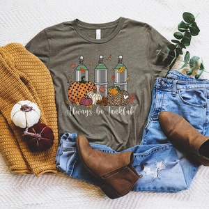 May include: A green t-shirt with a graphic of three silver canisters, pumpkins, and fall leaves. The text "Always be Tankful" is printed below the graphic.