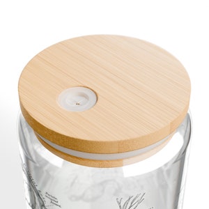 May include: A clear glass jar with a bamboo lid and a white silicone seal. The jar has a black and white illustration of a plant on the side. The lid has a small hole in the center.